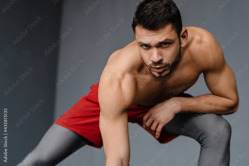 Young shirtless sportsman doing exercise while working out indoors Young shirtless sportsman doing exercise while working out indoors