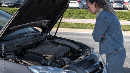 Broken down car. Vehicle engine motor problem concept. Driver girl near open hood auto.