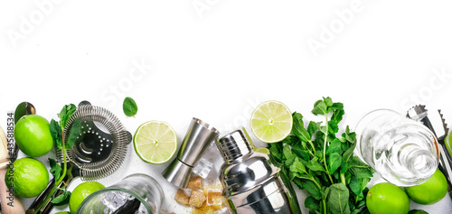 Mojito cocktail preparing ingredients: lime, mint, ice and bar tools, white background, top view photo