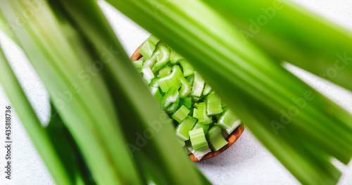 Chopped green celery in bowl, white table background, top view, copy space photo