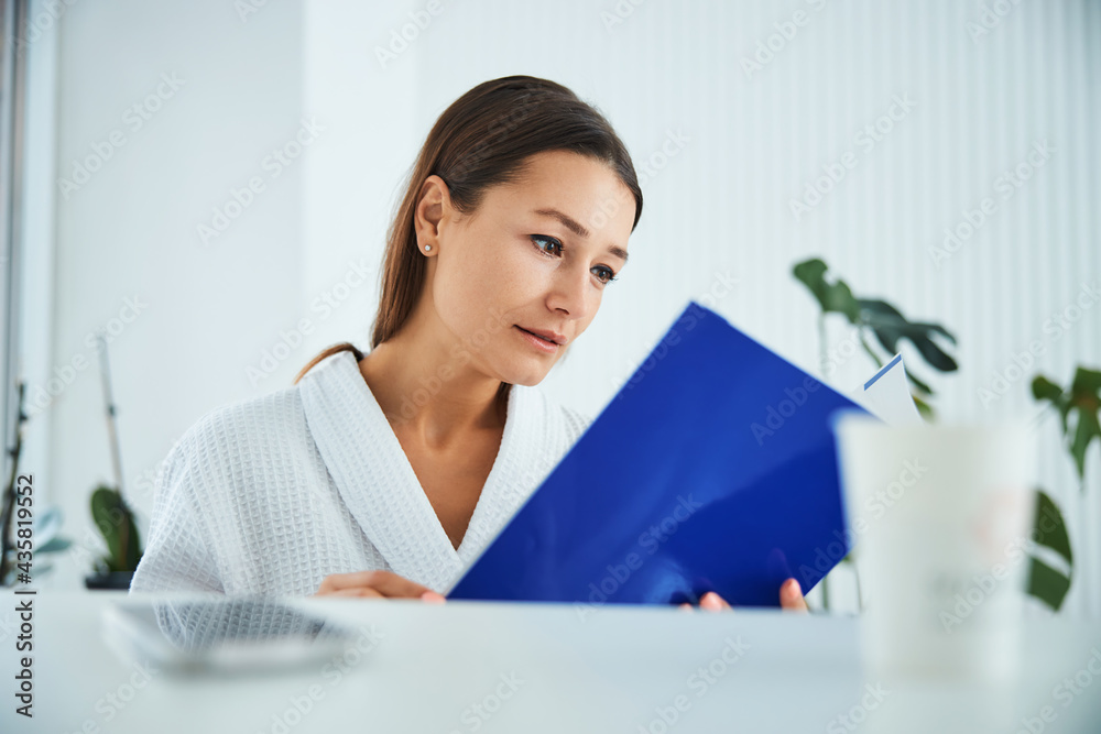 Concentrated lady client perusing a beauty salon brochure Concentrated lady client perusing a beauty salon brochure
