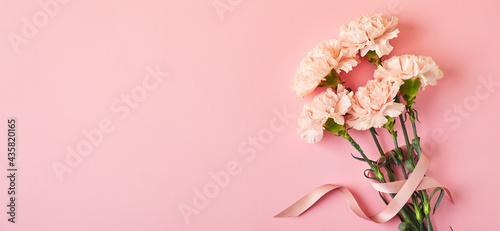 Bouquet of pink carnations. Design concept of holiday greeting with carnation bouquet on pink table background