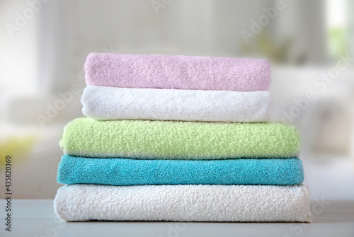 Colorful terry towels stack on table indoors. Bathroom shower items. Household.
