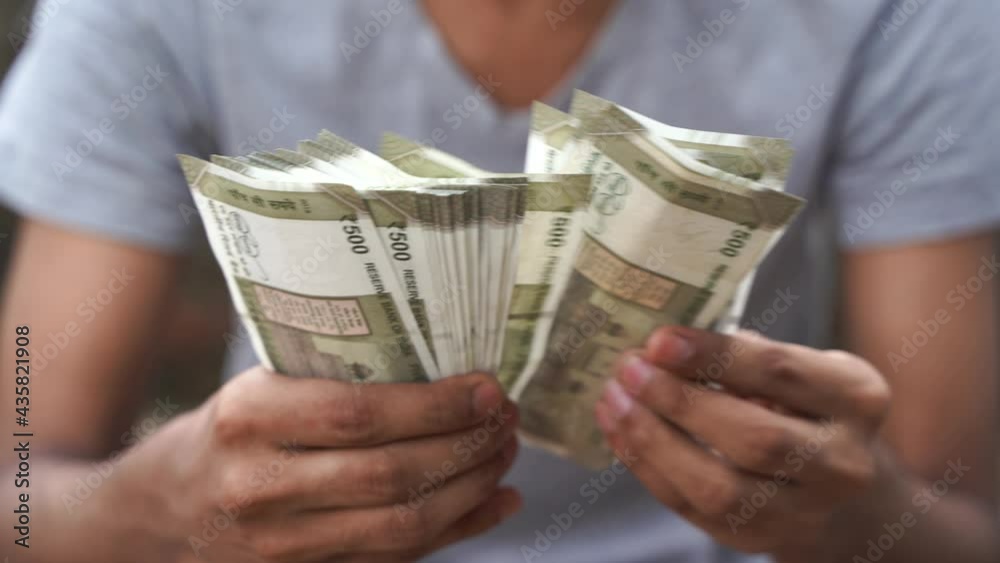 Unrecognizable young man counting five hundred Indian rupees, Close up of hand counting cash.