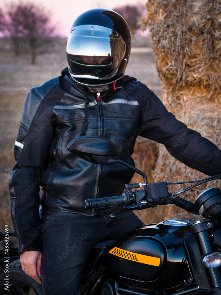 Naklejka premium Biker man with his motorcycle at sunset. Biker in the sunset light. Looking for adventure and freedom. Lifestyle photography