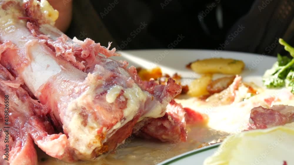 Male hands with knife and fork cut and eat freshly cooked delicious pork knuckle in restaurant Male hands with knife and fork cut and eat freshly cooked delicious pork knuckle in restaurant