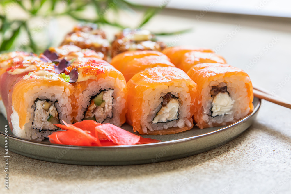 Assortment of sushi rolls served with ginger, sticks on ceramic plate. Sushi menu. Japanese food. Assortment of sushi rolls served with ginger, sticks on ceramic plate. Sushi menu. Japanese food.