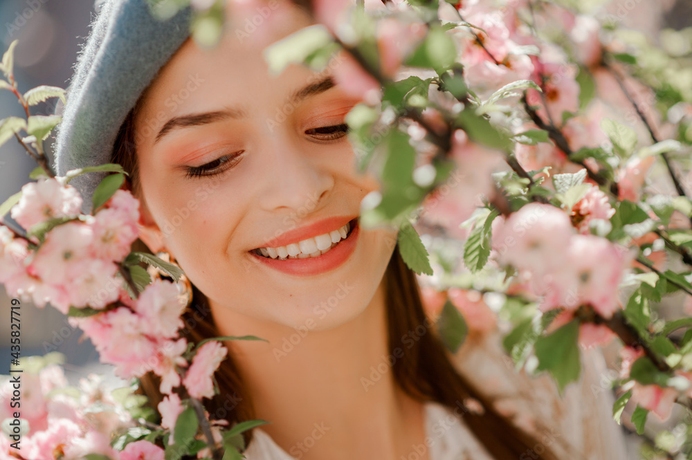 Fototapeta premium Happy smiling beautiful girl with natural makeup posing near blooming sakura flowers. Model closed eyes. Close up outdoor portrait. Spring, beauty, skin care, conception. 