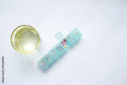 pill box fill with medical capsule and glass on white background  photo