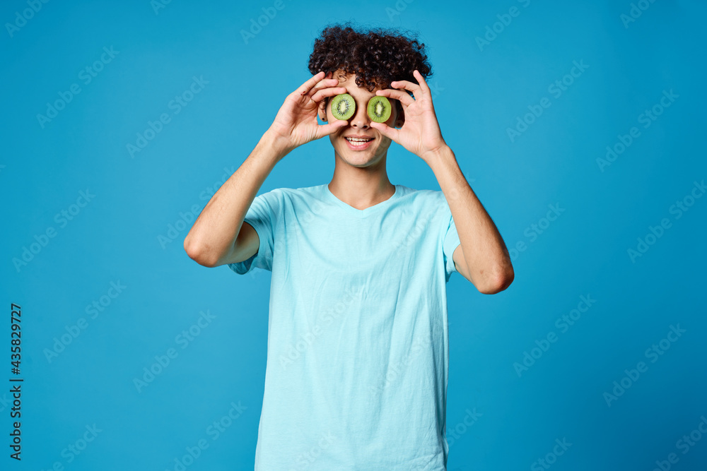 Cheerful guy curly hair kiwi near eyes isolated background Cheerful guy curly hair kiwi near eyes isolated background