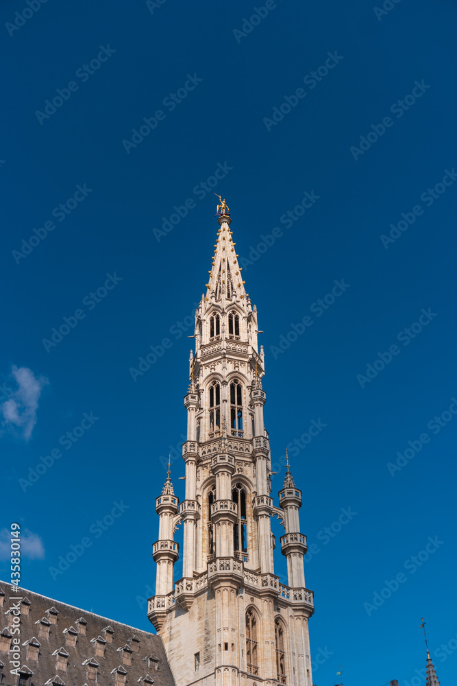 Brussels, Belgium. Town hall tower in the Gothic style against the blue sky.
