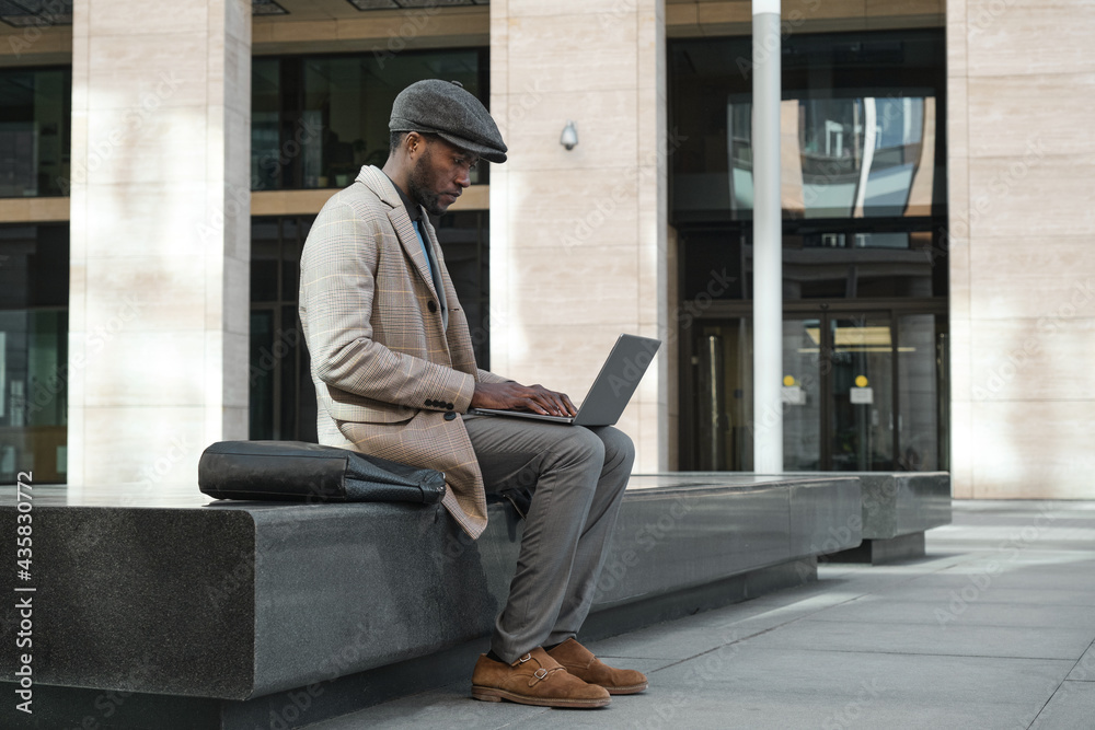 African young businessman typing on laptop he working online while sitting in the city