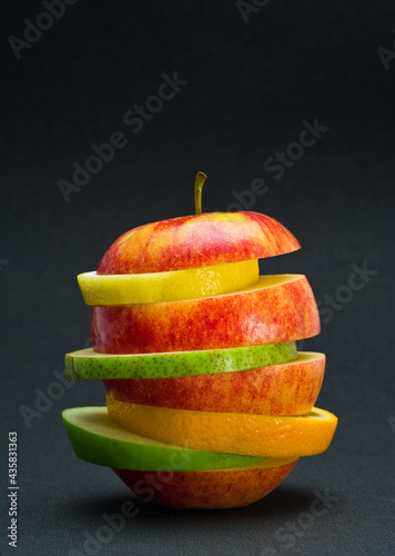 Variety of fruit slices stacked to resemble an apple. Healthy eating concept.