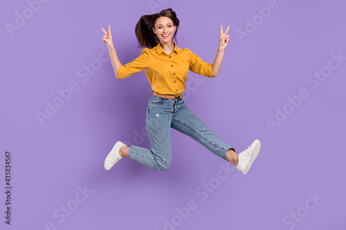 Full length body size photo jumping girl smiling overjoyed showing v-sign isolated pastel purple color background