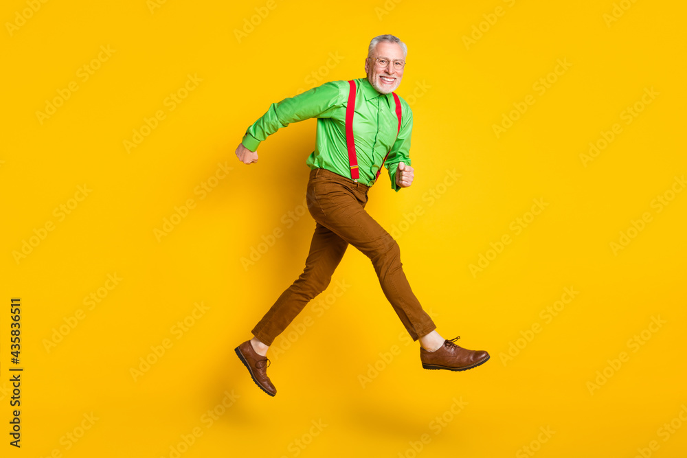Full body profile side photo of cheerful happy old man run go empty space isolated on yellow color background