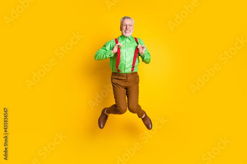 Full size photo of aged man happy positive smile have fun jump up isolated over yellow color background