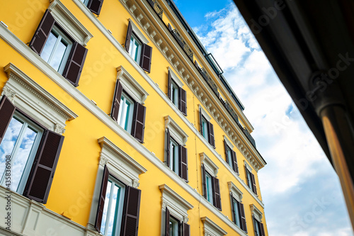 Low angle shot showing details of European classic building with beautiful Italian architectural style window panels located on street of Rome in Italy