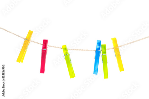 Colorful plastic clothespins hanging on rope against white background © New Africa