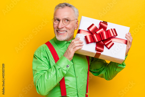 Photo portrait elder gentleman keeping guess what inside present box smiling isolated bright yellow color background
