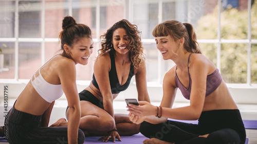 Group of girls in fitness class using mobile phone at the break