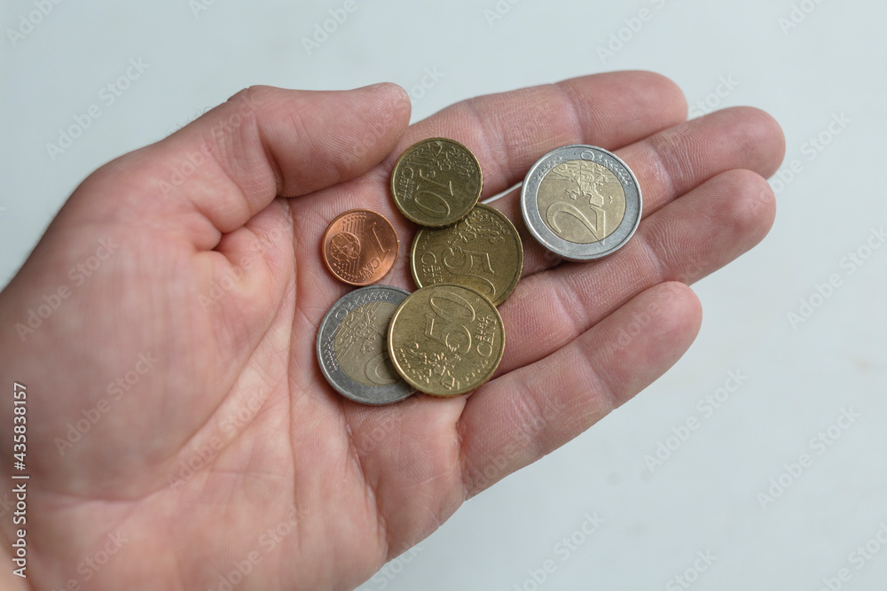 Male hand holds euro coins. European currency with hand on a white background. Male hand holds euro coins. European currency with hand on a white background.