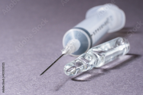 Medical ampoule and a syringe are on the table.