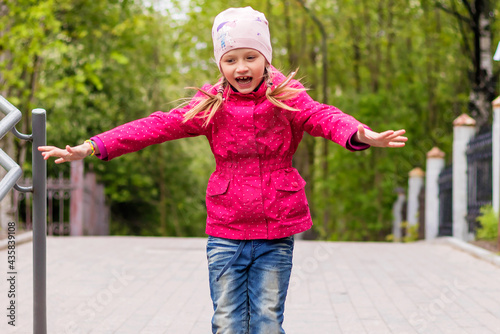 Cheerful happy girl on a walk in a jump with outstretched arms to the side. photo