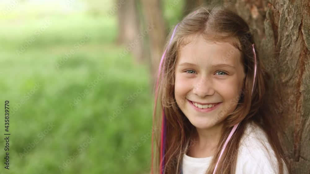 portrait of a happy little girl with long hair on a summer walk. colored strands of hair on hairpins. high quality 4K video footage portrait of a happy little girl with long hair on a summer walk. colored strands of hair on hairpins. high quality 4K video footage