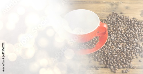 Composition of red cup and saucer with coffee beans over wooden surface with copy space