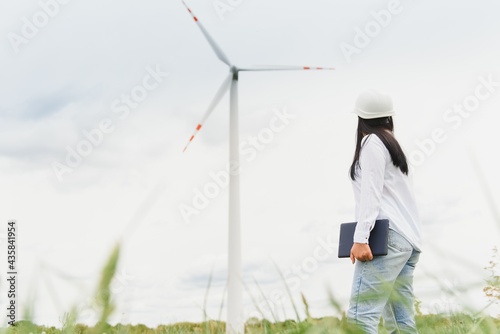 Women engineer using tablet for working on site at wind turbine farm © Serhii