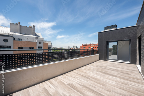 large terrace on a penthouse with clear skies and a large glass door in the background