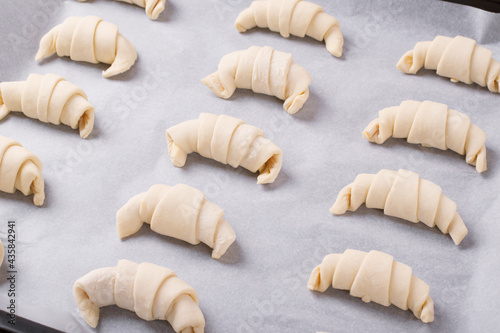 Raw croissants with filling prepared to be baked on the parchment. Making bakery products at home photo