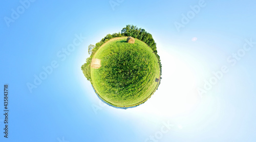 Stereographic projection of a green field with trees. 360 degree panorama. Globe panorama.