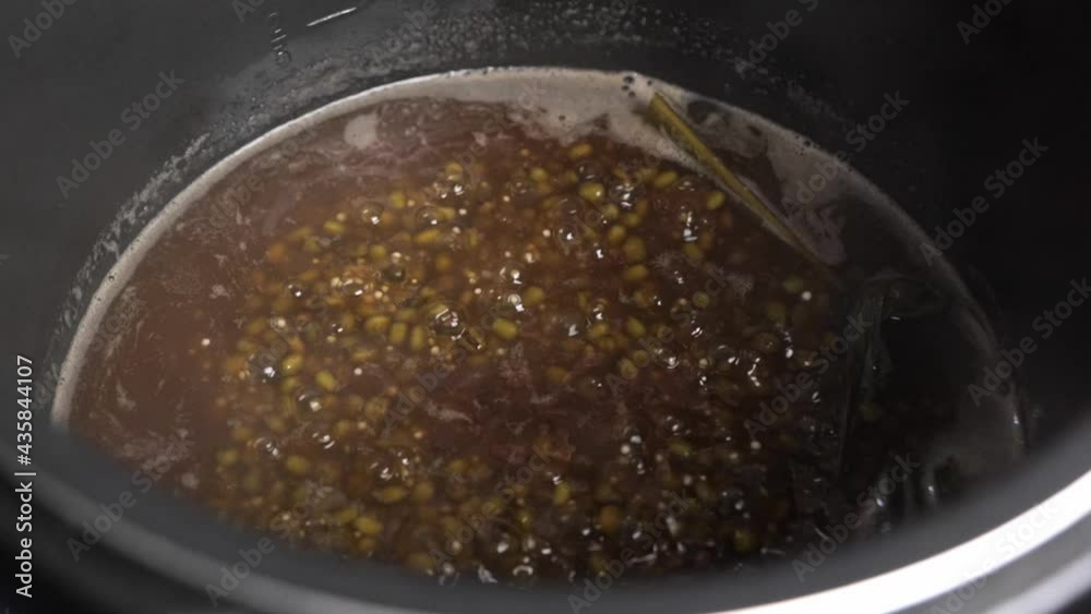 The coconut milk added to a pot of Green bean porridge or bubur kacang hijau. Cooking and adding ingredients.