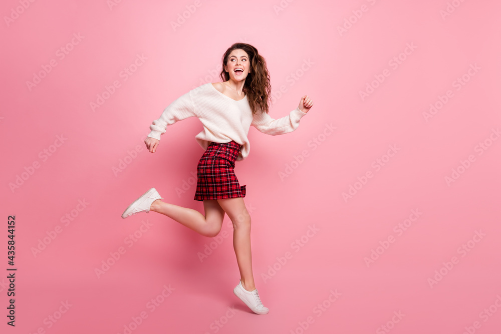 Full length profile side photo of young attractive girl happy positive smile jump up go walk run isolated over pink color background Full length profile side photo of young attractive girl happy positive smile jump up go walk run isolated over pink color background