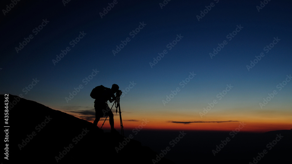 Photographer Silhouette at sunrise concentrating on the shot