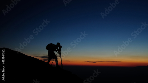 Photographer Silhouette at sunrise concentrating on the shot
