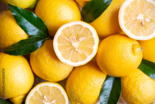 Fresh and ripe lemons with leaves on white wooden table