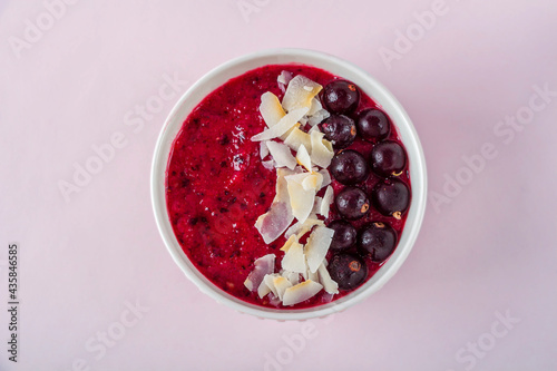 Female hand holding smoothie bowl with acai, banana, blueberries, kiwi fruit and black currants. Healthy super food with fresh fruit. Vegetarian and organic nutritional food