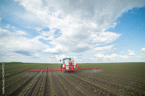 Tractor spraying pesticides at corn fields