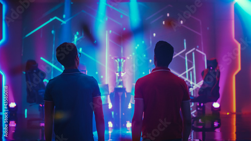 Two Professional eSports Gamers walking on Stage to Participate in the Cyber Games Championship Event. Competitive Online Live Streaming Tournament. Stylish Back View Shot