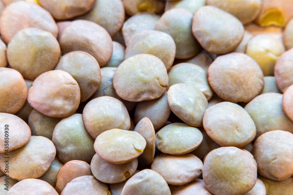 Background with raw lentils. Lentil grains on a wooden surface. blurry in soft focus at high magnification. Details on the surface of the grains. Background with raw lentils. Lentil grains on a wooden surface. blurry in soft focus at high magnification. Details on the surface of the grains.