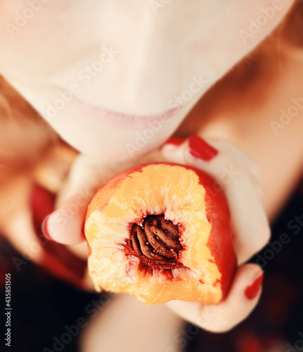 Beautiful young woman eating a peach