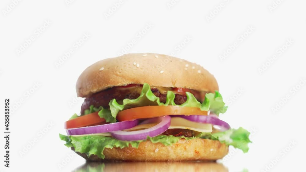 Big and tasty burger is rotating on the plate. Close up isolated footage at a white background Big and tasty burger is rotating on the plate. Close up isolated footage at a white background