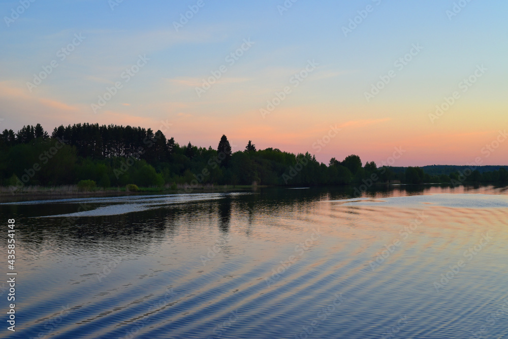 Early morning. Sunrise. View from the river with the reflection of the shore in the water and the wake of the ship. Early morning. Sunrise. View from the river with the reflection of the shore in the water and the wake of the ship.