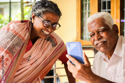 Elder couple enjoying social media in mobile phone at their home