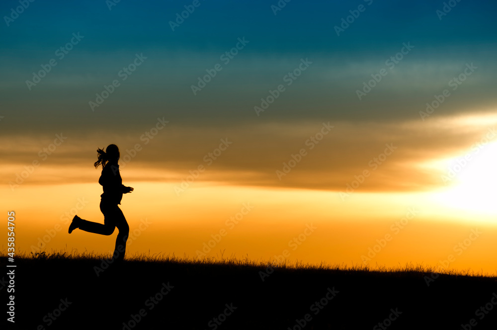 Silhouette of girl running in sunset.