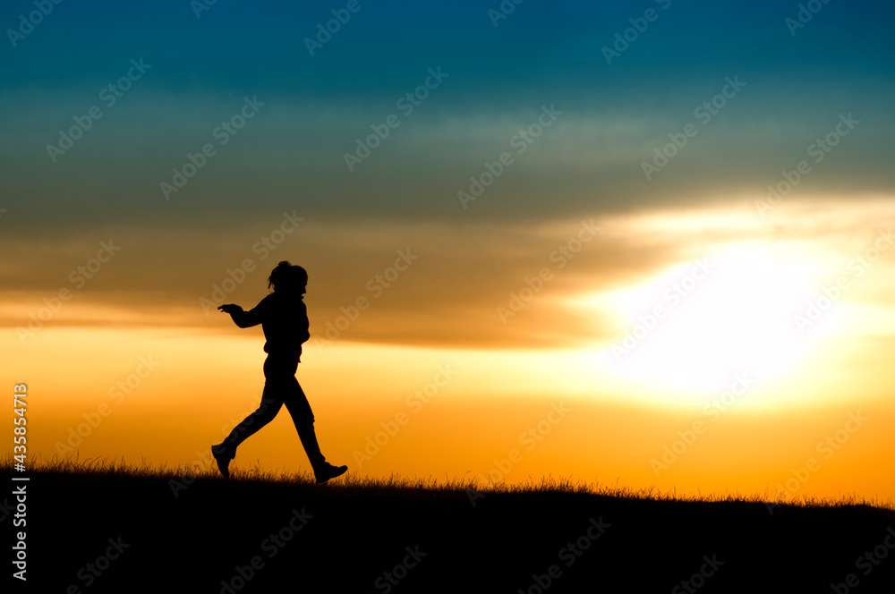Silhouette of girl running in sunset.