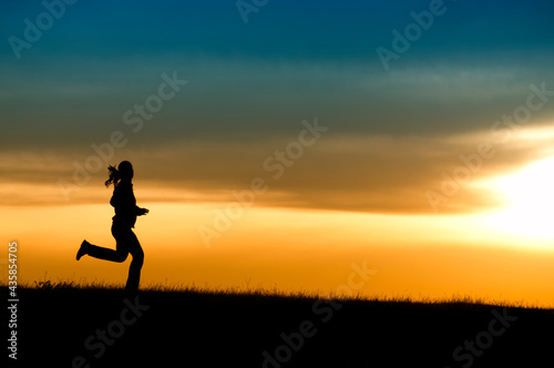 Silhouette of girl running in sunset. © Mihai