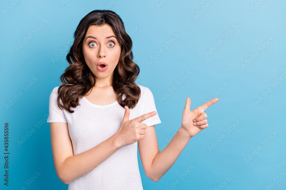 Photo of adorable impressed young lady dressed white outfit smiling pointing fingers empty space isolated blue color background Photo of adorable impressed young lady dressed white outfit smiling pointing fingers empty space isolated blue color background